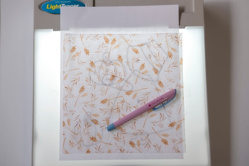 use a lightbox to trace the pattern onto your base fabric